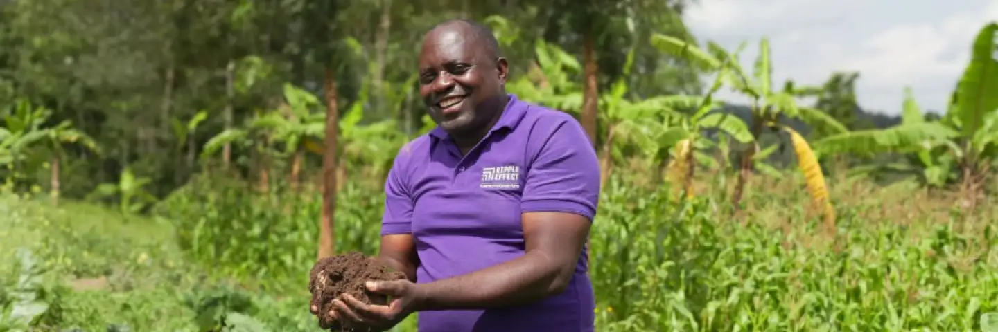 A Ripple Effect staff holding soil while standing in the middle of a field
