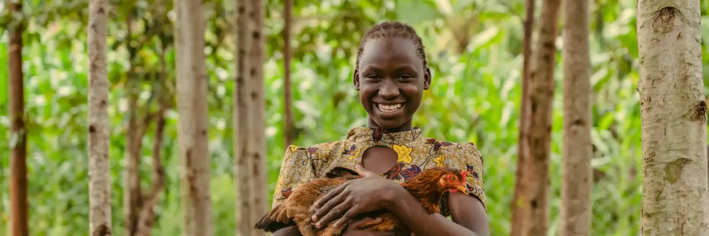 Mercy, a young woman, holding her chicken and smiling