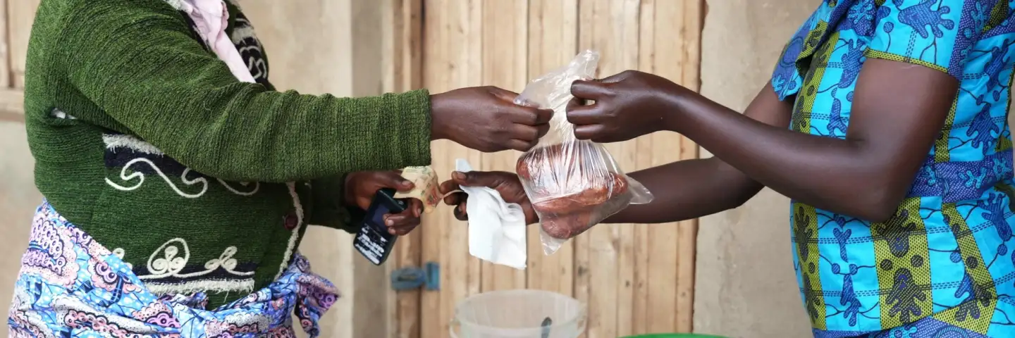 Two Burundian women are exchanging sweet potatoes for money