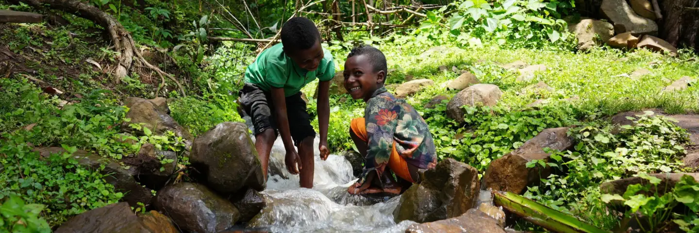Two young Ethiopian boys, playing by a stream