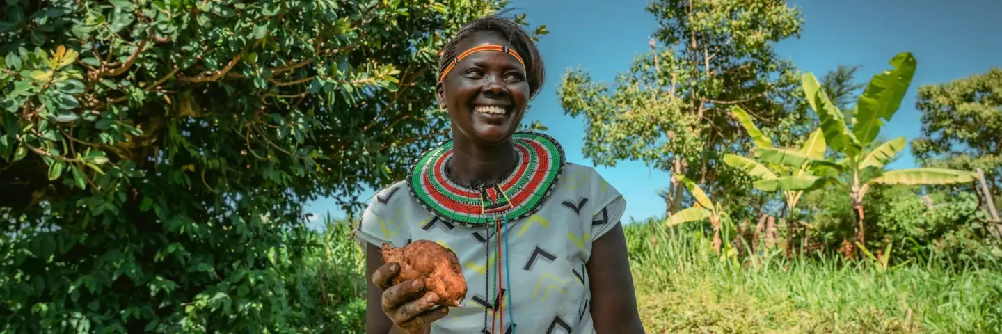Kenyan woman with her banana plantation, wearing a bright green and yellow dress