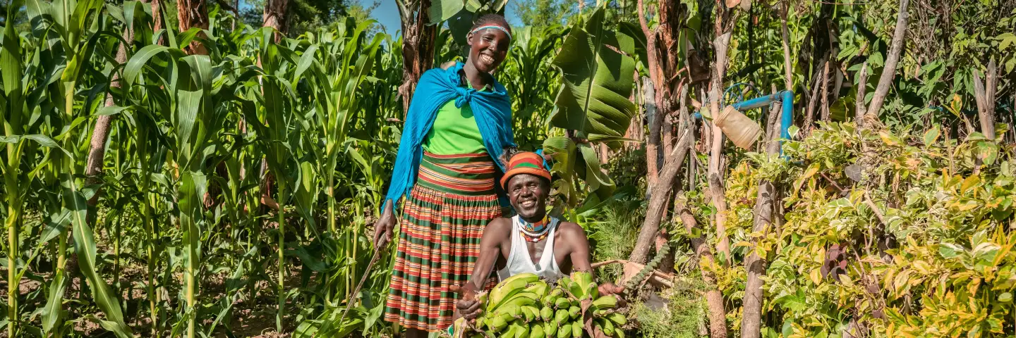 A man and a women with banana harvest, posing for a photo
