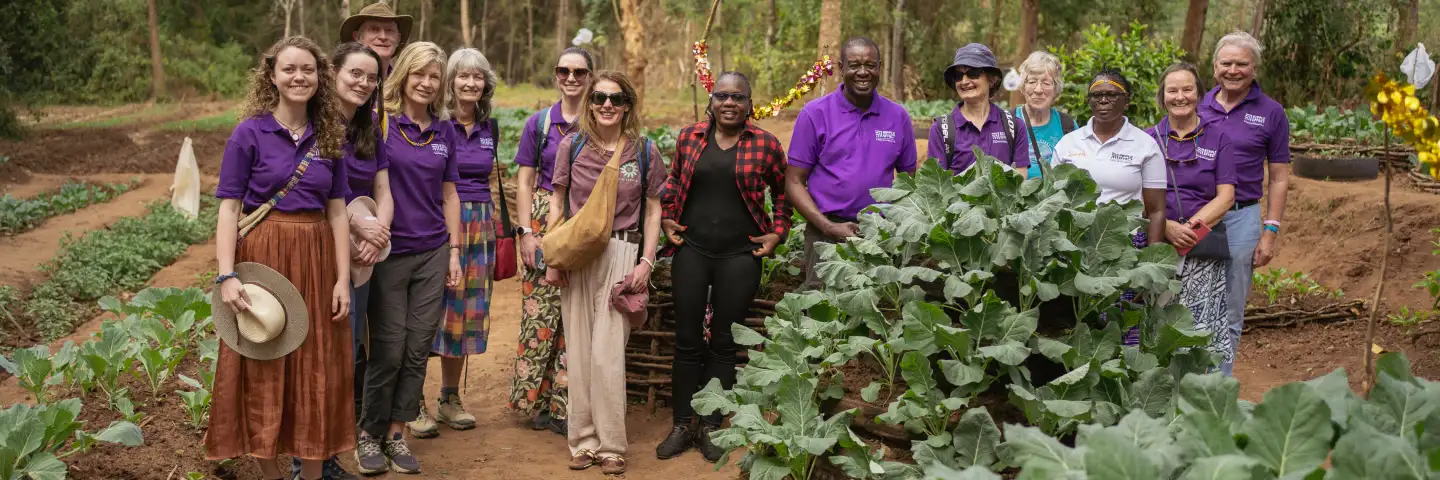 Group standing together in a vegetable garden surrounded by leafy crops