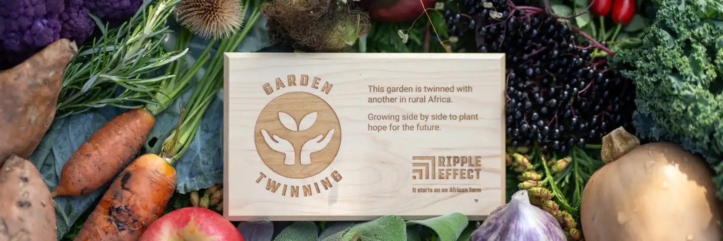 Man holding garden twinning plaque standing in front of a garden