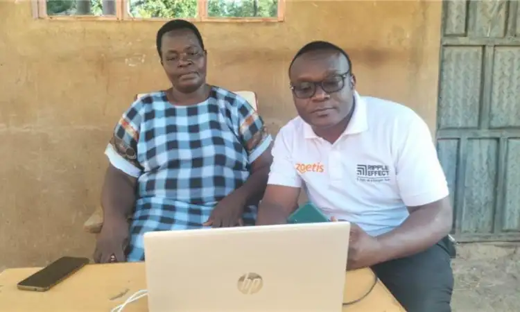A Kenyan farmer and a Ripple Effect Country Director sitting together with a laptop preparing for a meeting.