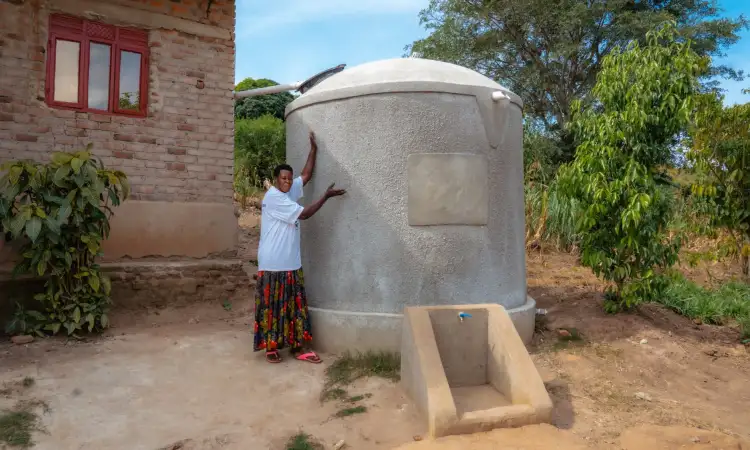Sarah, a project participant in Uganda, and her new large cementwater tank