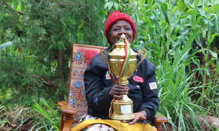 An Ethiopian woman is smiling and holding a large gold trophee