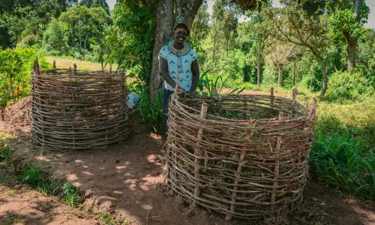 Priscillah, project participant in Kenya, with her two large compost heaps used as organic fertiliser