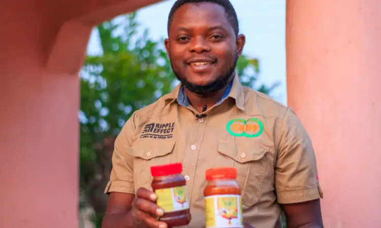 ZRDF field officer smiling and proudly holding two jars of honey produced by participants
