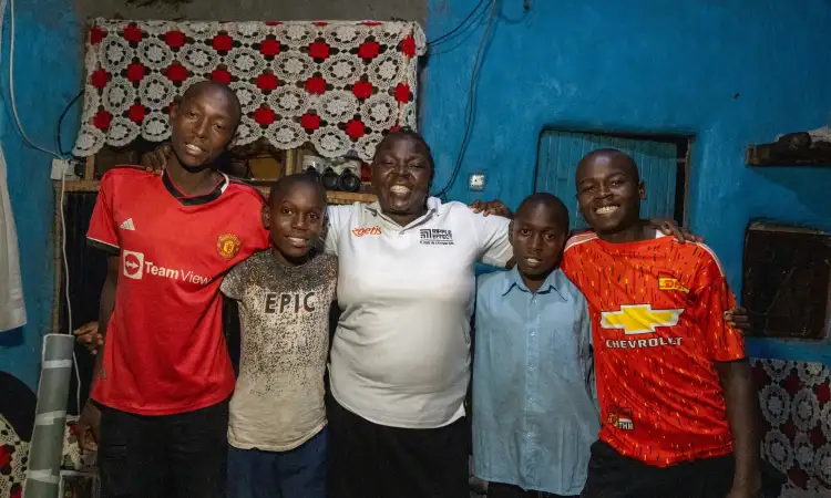Florah and her four children, linking arms and smiling in their home