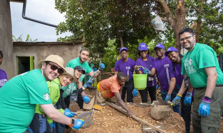Group of people working together outdoors with buckets and building materials