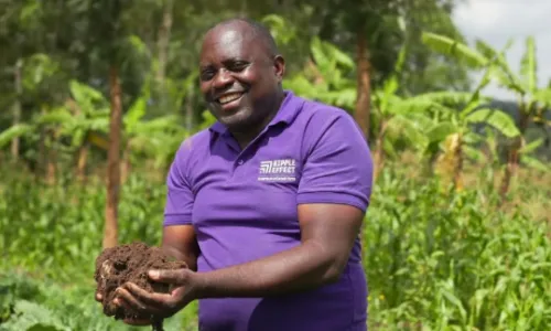 A Ripple Effect staff holding soil while standing in the middle of a field