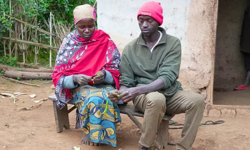 Couple sitting together outside their home discussing and preparing produce