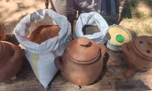 Bags of grain and seeds displayed alongside traditional clay pots on a wooden table.
