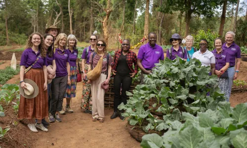 Group standing together in a vegetable garden surrounded by leafy crops
