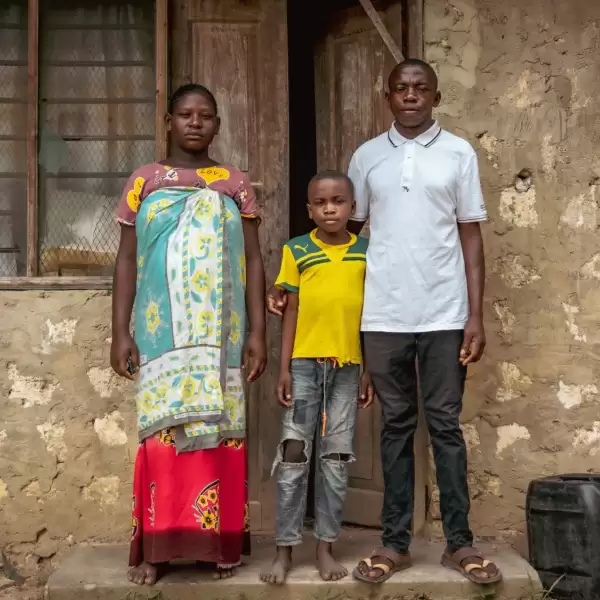 Sikukuu, her son Juma and her husband Mr Ibrahim outside their house