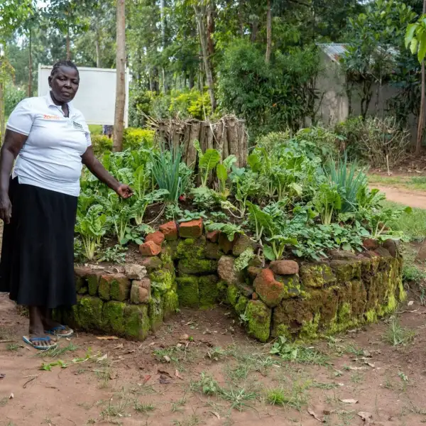 Kenyan woman standing next to her keyhole garden
